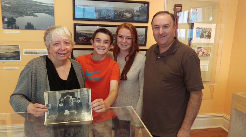 Three generations of the Rossi family: Rose Marie poses with her nephew Ron Forsell and grandchildren Grace and Matt, while holding a photo of her own mother and grandfather at the PPIE.